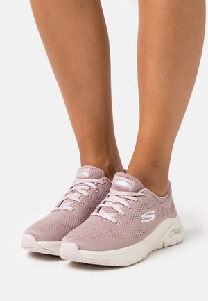 Chaussures de sport rose clair avec une tige en mesh, un bout rond et une semelle rembourrée. Les caractéristiques comprennent des lacets et une marque sur la languette et sur le côté.