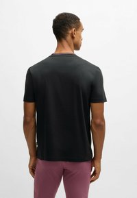 Black cotton t-shirt with short sleeves and a round neckline. Features a contrasting ribbed collar and a relaxed fit. Smooth texture.