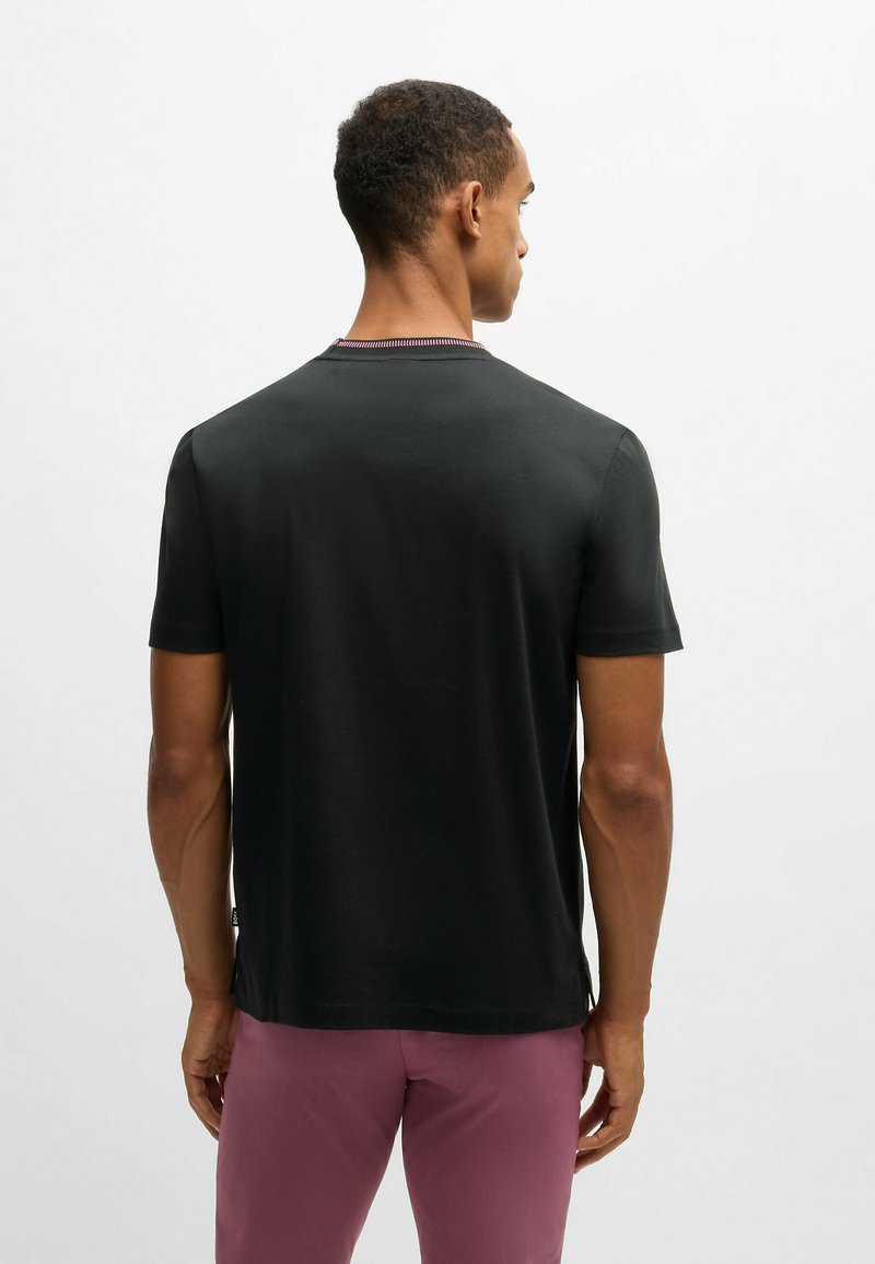 Czarna bawełniana koszulka z krótkim rękawem i okrągłym dekoltem. Posiada kontrastowy ściągacz przy kołnierzyku oraz luźny krój. Gładka faktura.