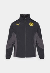 Schwarze Jacke mit grauen Akzenten, hohem Kragen, Reißverschluss vorne und gelbem Logo. Verfügt über eine glatte Textur und leichtes Material.