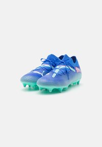 Blue soccer cleats with a textured upper, featuring light blue accents and a mint green sole. Designed for traction with molded studs.