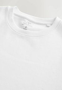 Fehér, pamutból készült, környakú póló normál szabással. Sima textúrájú, címkéjén márkanév, fazon és ápolási útmutató található.