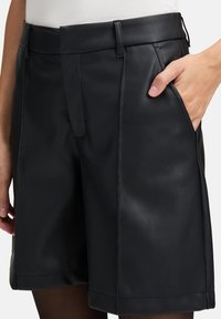 Zwarte neplederen shorts met een op maat gemaakt ontwerp, voorzien van een platte voorkant, zijzakken en een gladde textuur.