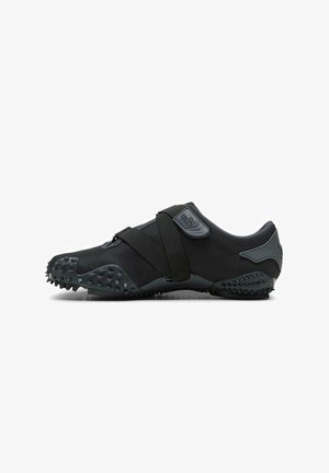 Schwarzer Sportschuh mit Obermaterial aus strukturiertem Stoff, Gummisohle mit Stollen für besseren Halt und einem verstellbaren Riemen über dem Mittelfuß.