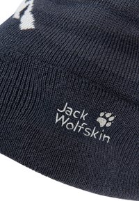 Strickmütze in Marineblau mit gerippter Struktur. Mit weißem Logo „Jack Wolfskin“ und Pfotenabdruck. Das Material wirkt weich und flexibel.