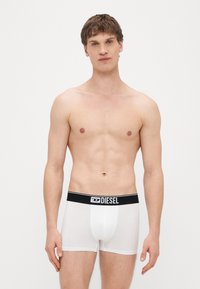 Cuecas boxer em algodão branco com cós elástico preto com o logotipo da Diesel. Design simples e forma ajustada.