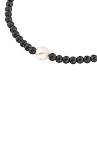 Collar de cuentas negras con un gran centro en forma de perla blanca lustrosa; textura mate y tamaño de cuentas uniforme en toda su extensión.