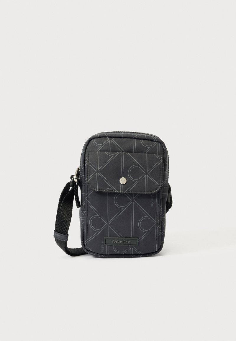 Kompaktne must risti-keha kott geomeetrilise mustriga, esiküljel klapiga tasku koos trukknupuga ja reguleeritav kangast õlakinnitus.