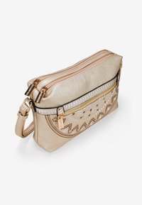 Bolso crossbody metálico dorado con patrones geométricos en relieve, compartimentos con doble cremallera y una superficie texturizada. Se incluye una correa ajustable.