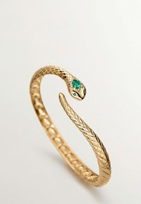 Pulsera en forma de serpiente de oro con un diseño texturizado y trenzado. Presenta una piedra verde en la cabeza, que añade detalle a la forma elegante en general.