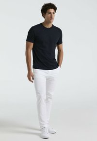 Marineblauwe crew-neck t-shirt van katoen met een subtiele logodetail. Gecombineerd met witte slim-fit broek en witte sneakers.