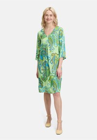 Groene jurk met paisleypatroon, driekwartmouwen, v-hals en een relaxte pasvorm, gemaakt van lichte stof.