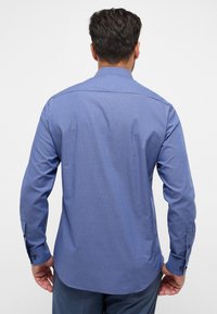 Camicia a manica lunga a quadretti blu con polsini abbottonati, caratterizzata da un colletto allargato e una trama di tessuto liscia. Visualizzazione della parte posteriore.