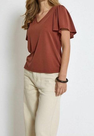 T-shirt à col en V couleur rouille avec manches courtes plissées, associée à un pantalon large couleur écrue. Tissu lisse, design décontracté.