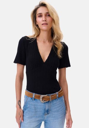 Zwart geribbeld bodysuit met een diepe V-hals en korte mouwen, gecombineerd met lichtblauwe jeans met hoge taille en een bruine riem met zilveren sluiting.