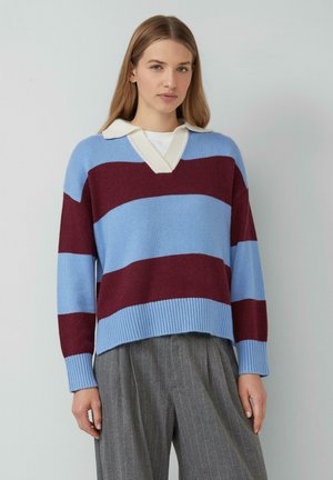 Gestreifter Baumwollpullover in Blau und Burgunderrot mit einem cremefarbenen Polokragen, V-Ausschnitt und gerippten Bündchen, kombiniert mit grauen, gefalteten Hosen.