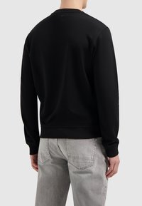 Zwart sweatshirt van zachte stof, met een ronde halslijn, ribgebreide manchetten en een zoom. Zichtbare stikdetails en een minimalistisch ontwerp.