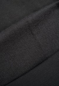 Czarna tkanina o miękkiej, puszystej teksturze, zestawiona z sekcją prążkowanego dżerseju. Gładka, jednolita powierzchnia bez widocznych wzorów czy akcentów.