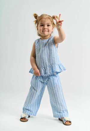 Conjunto de algodón a rayas de color azul claro que incluye un top con peplum y pantalones holgados. Sandalias con un adorno de flor completan el look.