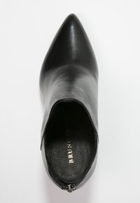 Botín de cuero negro con punta afilada y cremallera trasera, con plantilla con marca, mostrado desde una vista superior sobre fondo blanco.