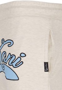 Sweatshirt beige clair avec un graphique de baleine bleue et un texte en contour noir. Comprend une étiquette logo discrète et une poche latérale.