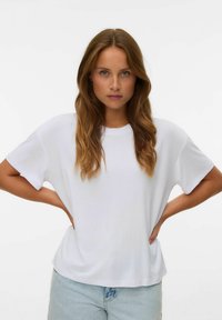 Vit bomulls-t-shirt med avslappnad passform och korta ärmar, med rund halsringning. I kombination med ljusblå denimshorts.