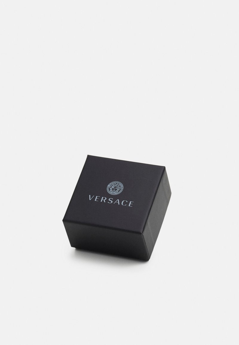 Scatola regalo nera con finitura opaca, con un logo Versace in rilievo argentato sul davanti. Design compatto e semplice.