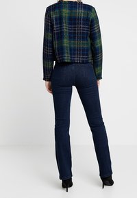 Veste à carreaux en mélange de laine aux couleurs bleu foncé, vert et jaune. Design ajusté structuré, longueur raccourcie, avec un col rond et des manches longues.