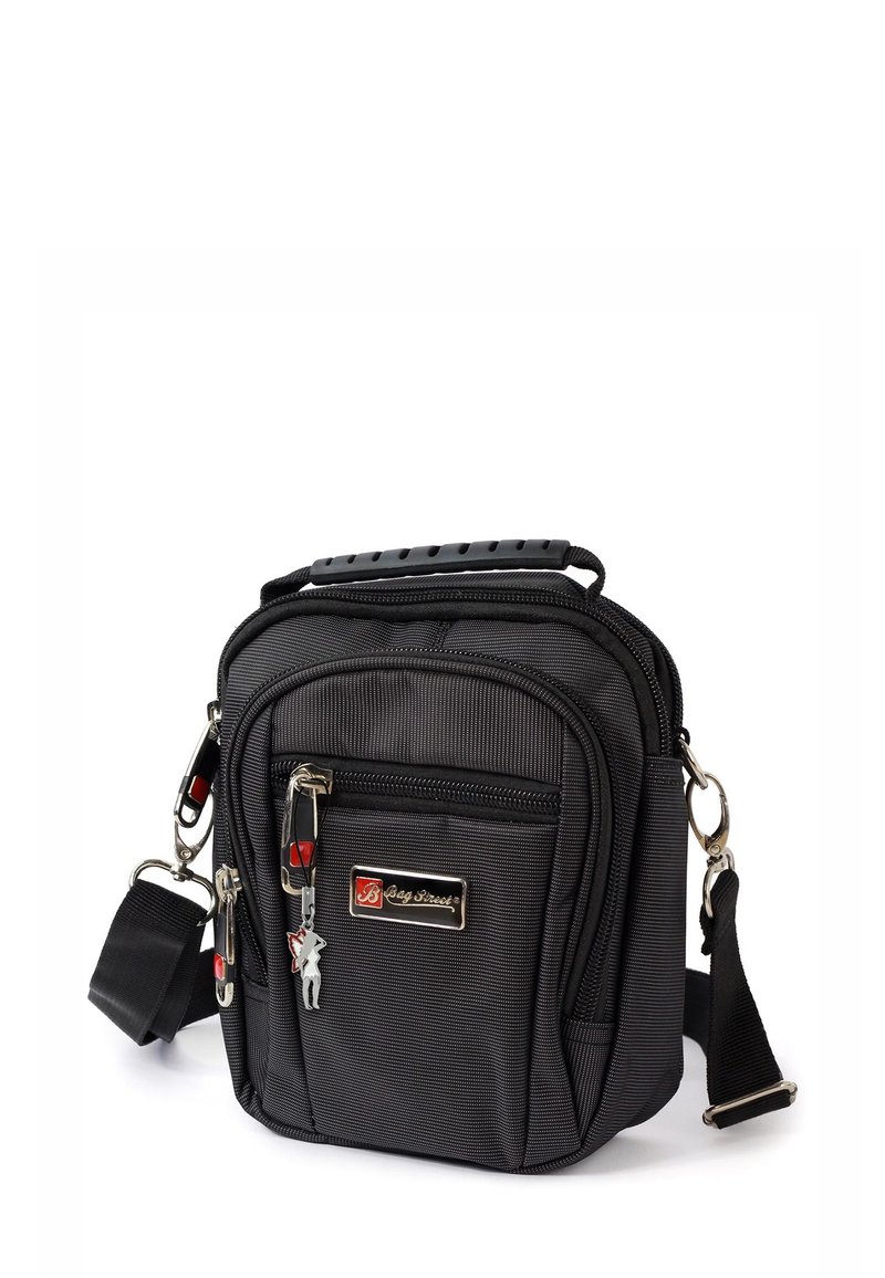 Schwarze Stoff-Schultertasche mit strukturierter Oberfläche, Reißverschlussfächern und abnehmbarem Schultergurt. Verfügt über ein silbernes Logo und einen dekorativen Schlüsselanhänger.