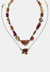 Due collane a strati con gemme multicolori nelle tonalità di ambra, viola e verde, montate in metallo dorato con dettagli intricati.