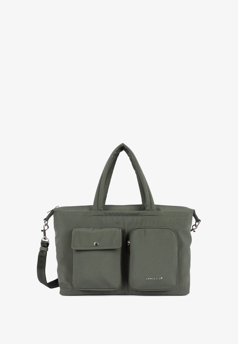 Borsa tote in tessuto khaki con doppi manici superiori, tracolla removibile, due tasche frontali e logo argentato sulla tasca inferiore.