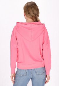 Felpa rosa con cappuccio, maniche lunghe, vestibilità rilassata e polsini a coste. Il tessuto sembra morbido e liscio, con un design semplice.