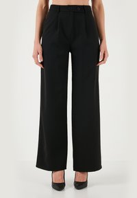 Black wide-leg trousers made from smooth fabric. Features a high waist, front pleats, and dual button closure. Designed for a relaxed fit.