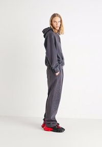 Grå hettegenser med lommer foran, sammen med matchende joggebukser med "STAR WARS" trykk. Svart og rød klumpete sneakers.