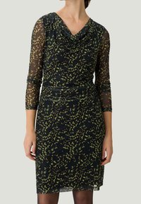 Czarna sukienka z zielonym kwiatowym wzorem, przeźroczystymi długimi rękawami i dekoltem w kształcie łódki. Dopasowany krój o teksturowanym wyglądzie.
