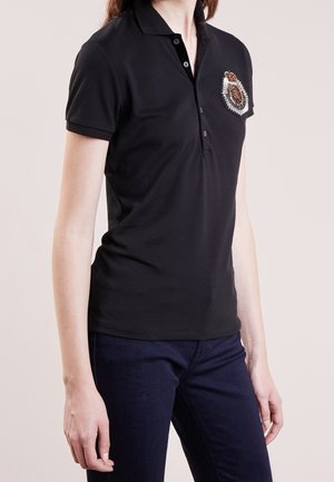 Schwarzes Polo-Shirt aus glattem Stoff, mit einer Knopfleiste mit vier Knöpfen und einem dekorativen Aufnäher auf der linken Brust.