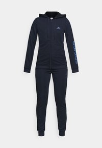 Chándal negro de mujer Adidas con sudadera con capucha y cremallera, logo en el pecho y la manga; pantalones ajustados a juego con tobillos puños.