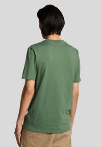 Grøn bomulds T-shirt med korte ærmer og rund hals. Har en subtil tekstur og et lille mærke på venstre ærme.