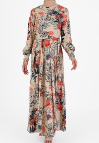 Langes Blümchenkleid mit beigem Hintergrund, das rote und marineblaue Blumen zeigt, lange Ärmel, einen Rundhalsausschnitt und einen fließenden Rock.