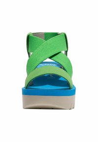 Sandali di tela verde con cinturini incrociati, plantare blu e piattaforma bianca. Presentano cinturini testurizzati e ammortizzazione per il comfort.