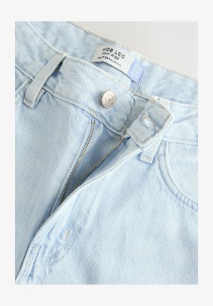 Svijetloplave široke traperice s visokim strukom. Izrađene od denima, s patentnim zatvaračem, metalnim kopčanjem i oznakom za njegu unutar struka.