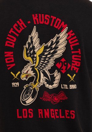 Aigle aux ailes déployées tenant une roue de moto, entouré du texte rouge "Von Dutch Kustom Kulture" et "Los Angeles" sur fond noir.