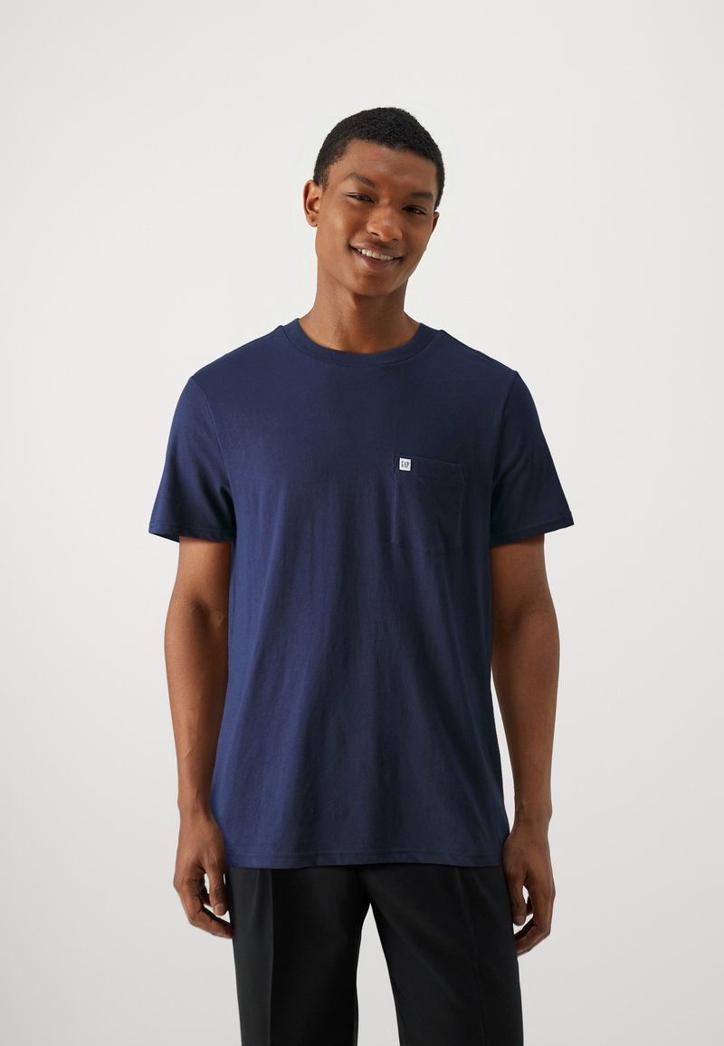 T-shirt à manches courtes en coton bleu marine, doté d'une petite poche poitrine et d'un col rond, avec une texture douce et une coupe décontractée.