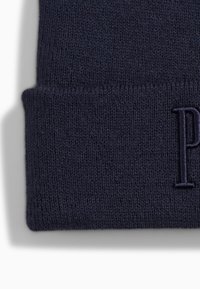 Tummansininen neulottu pipo taitetulla reunalla. Edessä on hillitty brodeerattu kirjain "P". Pehmeä pinta ja tiukka istuvuus.