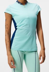 Lichtblauw atletisch shirt met korte mouwen, hoge kraag met een patroonaccent en marineblauwe zijpanelen; gemaakt van een gladde, rekbare stof.