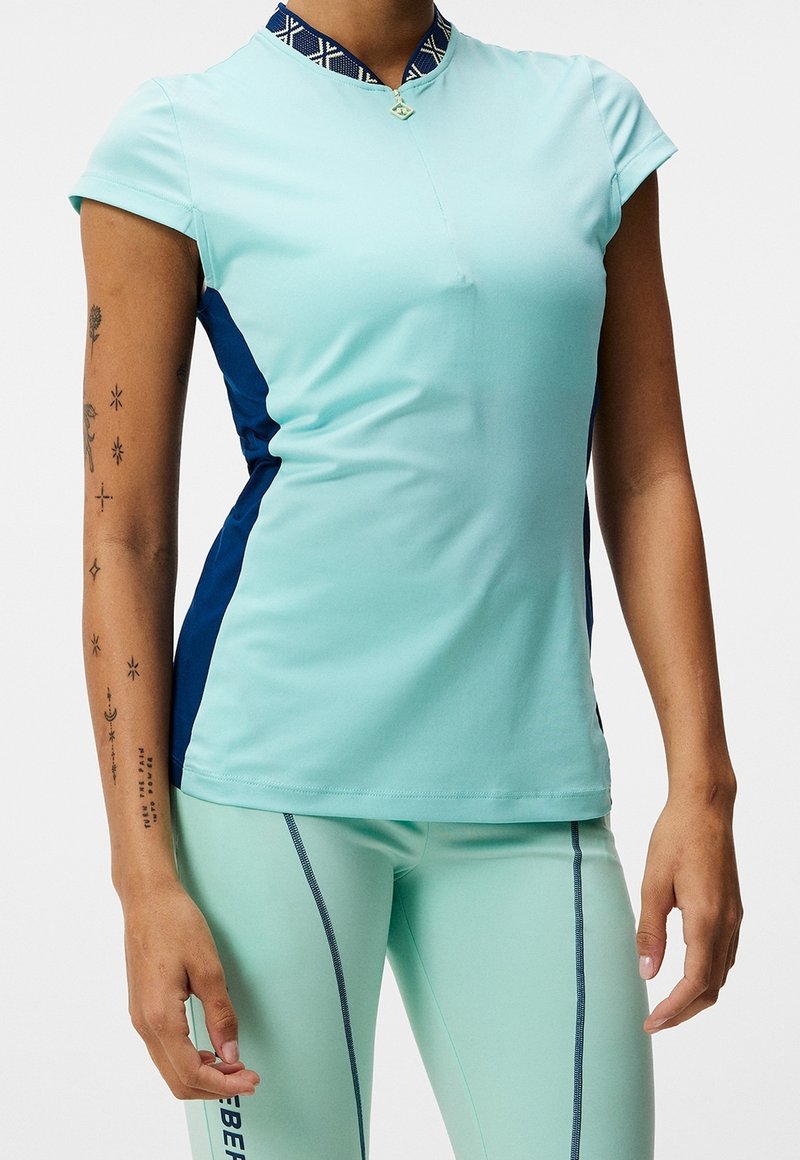 Lichtblauw atletisch shirt met korte mouwen, hoge kraag met een patroonaccent en marineblauwe zijpanelen; gemaakt van een gladde, rekbare stof.