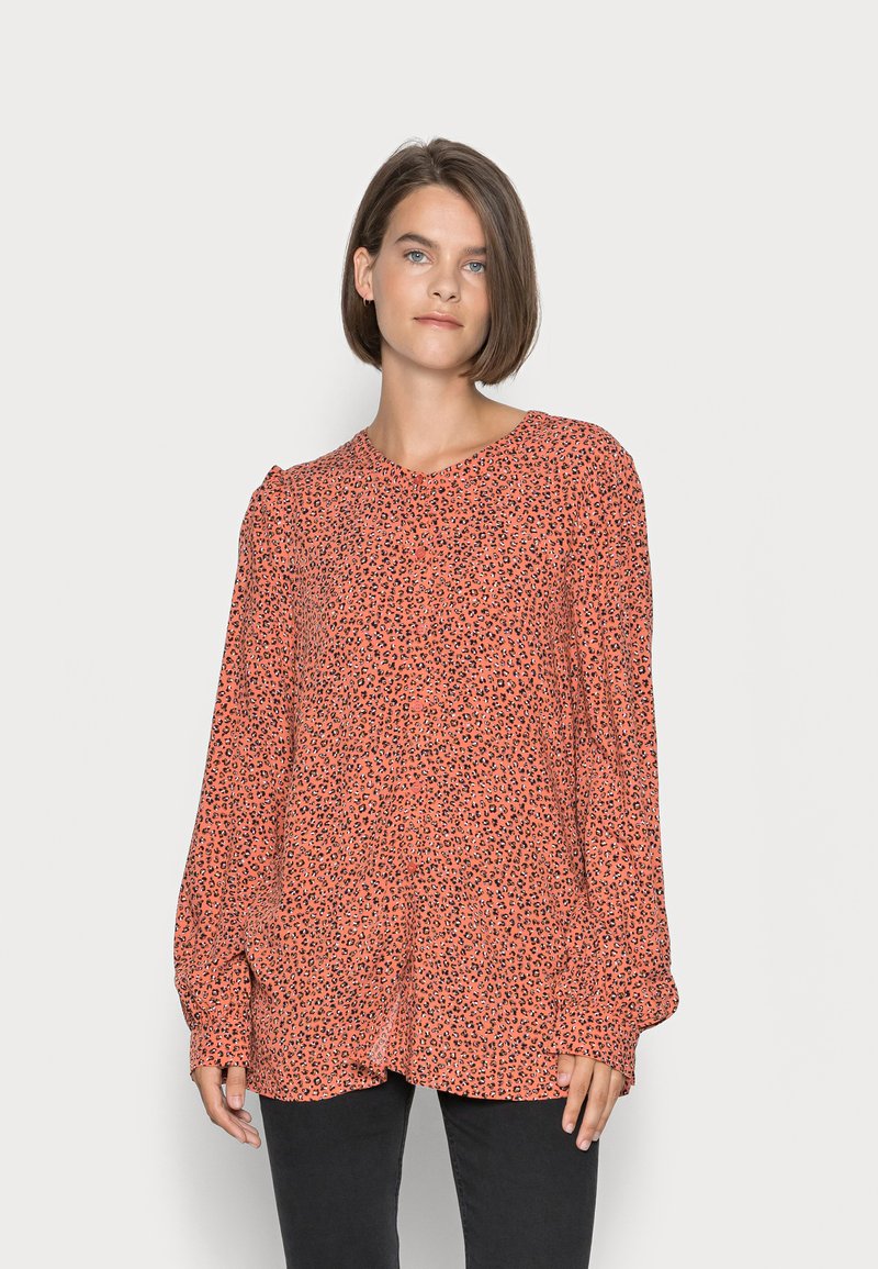 Blusa de manga longa em coral com um padrão de leopardo preto, apresentando um corte ligeiramente descontraído e decote redondo. Feita de um tecido leve.
