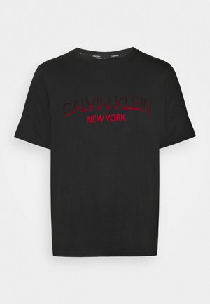 Sort T-shirt med korte ærmer med rød tekst "Calvin Klein New York" på forsiden og rund halsudskæring.