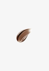 Une étale lisse et courbée de crème brune brillante ou de chocolat sur un fond blanc uni, mettant en valeur la texture et la brillance.