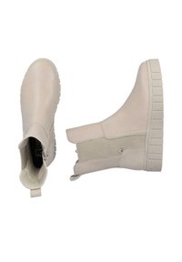 Botas de tobillo beige con un exterior sintético liso, paneles laterales elásticos texturizados y una suela de goma gruesa y estriada.
